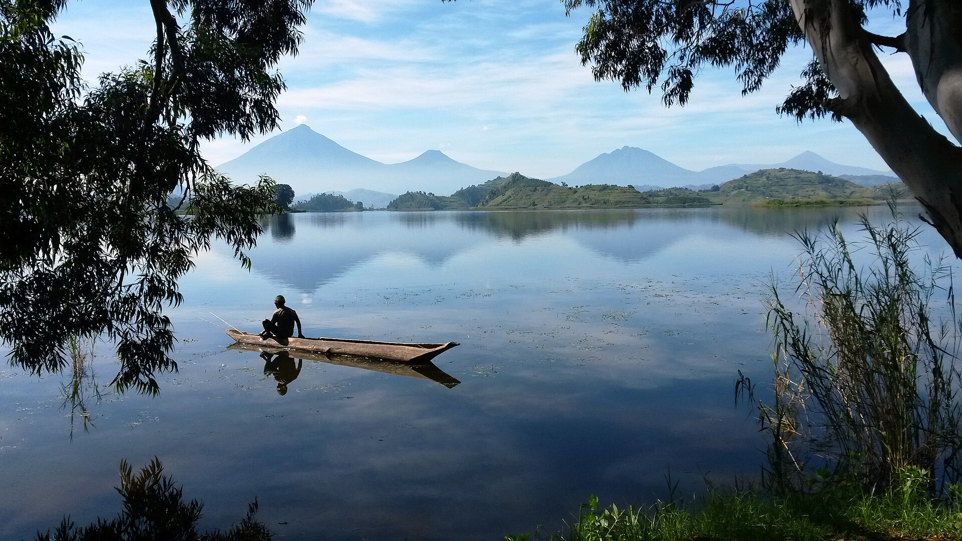 A wooden canoe on Lake Mutanda with the Virunga volcanoes in the distance